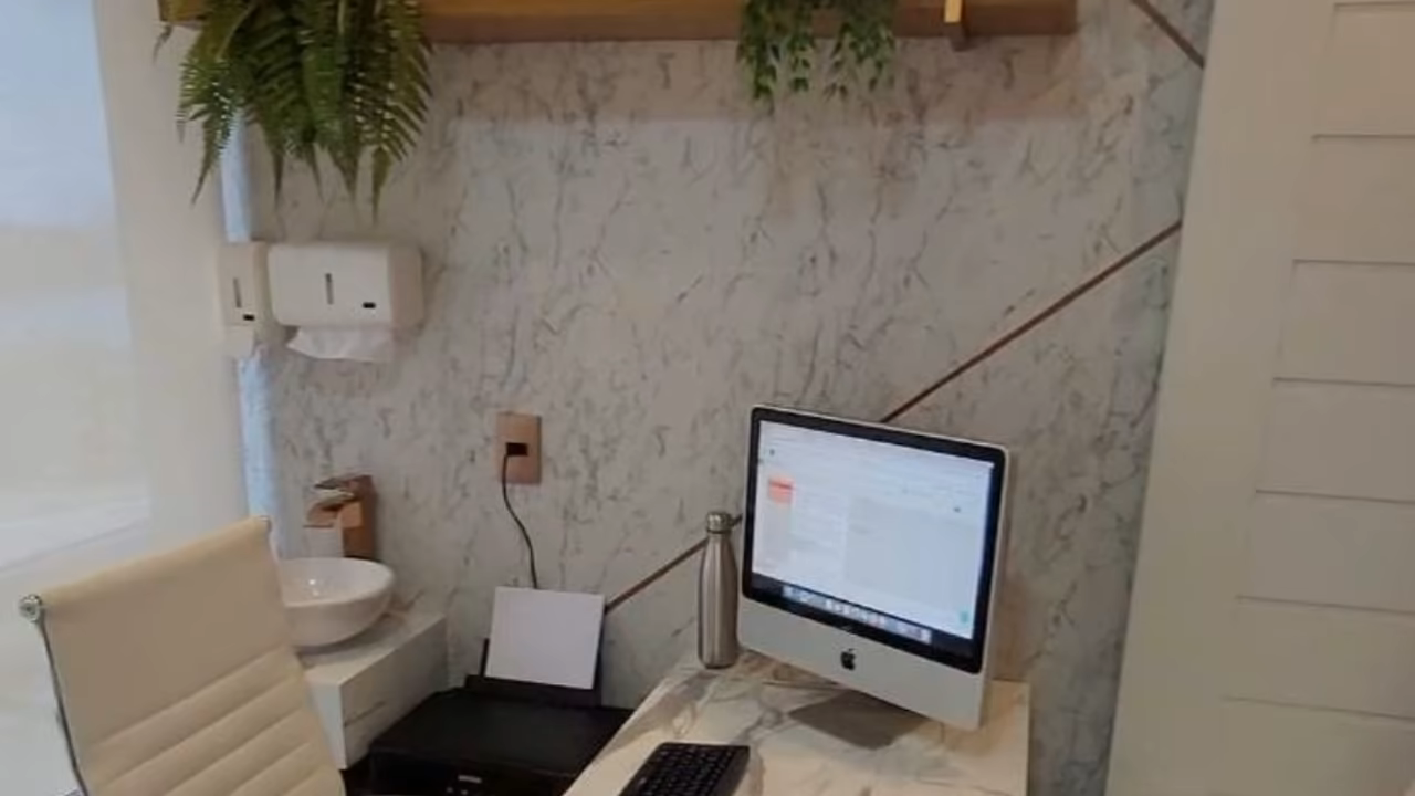 Consultório do Dr. Lucas no Planta Tower, com mesa de mármore, prateleiras de madeira e plantas
